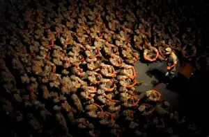 عکس از نمای بالا از تعدادی از تفندگداران دریایی آمریکا که نشته اند و به سخنرانی فرمانده خود که مقابل آنها ایستاده گوش می دهند