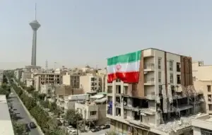 نمای دور از تهران که برج میلاد دیده می شود. در نمای نزدیکتر یک سمت ساختمان بلند تخریب شده و از سمت دیگر پرجم جمهوری اسلامی در ابعاد بزرگ نصب شده است