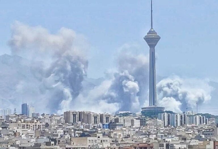 نمای دور از بمباران تهران که در آن برج میلاد دیده می شود و دورتر از آن دود به آسمان بلند شده است
