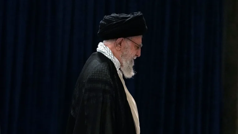 علی خامنه ای در حال راه رفتن در یک پس زمینه تاریک