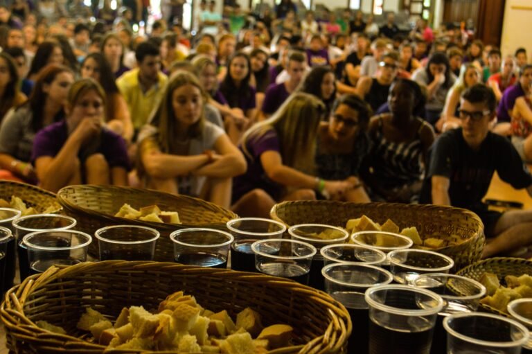 تعداد زیادی زن و مرد نشسته اند و آماده اند تا مراسم نان و شراب مقدس بخورند