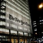 ساختمان شیشیه ای نیویورک تایمز در شب با چزاغ های روشن. روی ساختمان به انگلیسی نوشته شده است نیویورک تایمز