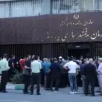 در روبروی سازمان هدفمندی یارانه ها حدود چهل نفر زن و مرد ایستاده اند. به نظر می رسد اعتراض دارند