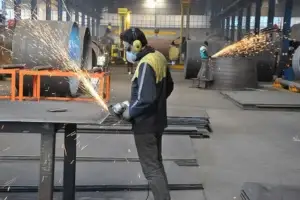 یک صنعتکار در حال کار با دستگاه سنگ فرز