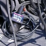 یک میکروفون مصاحبه که روی آن نوشته شده است فاکس نیوز. این میکروفون روی زمین است و سیم های سیاه رنگ زیادی اطراف آن ریخته شده است.