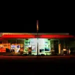 تصویر یک پمپ بنزین در آمریکا. تصویر در شب است و چراغ های بمب بنزین روشن. کسی داخل آن نیست