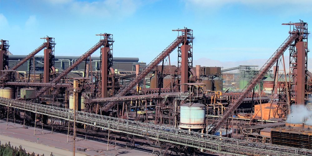 عکس از صنعت فولاد که در آن جند ستون فلزی می بینیم که از آنها بخار بلند شده است