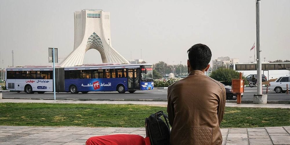 یک مرد پشت به تصویر دارد به میدان آزادی نگاه میکند