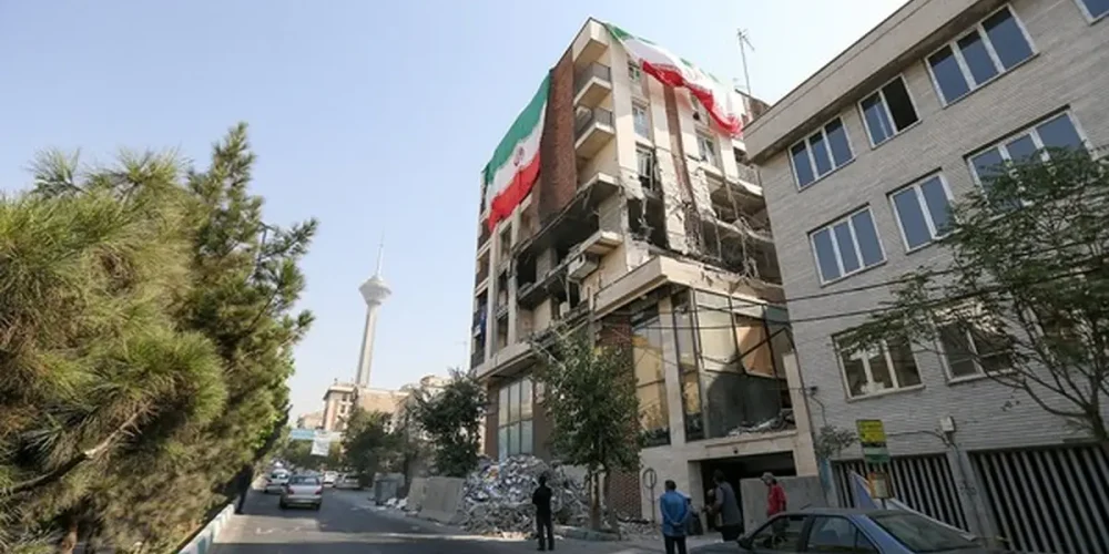 نمای دور از تهران که برج میلاد دیده می شود. در نمای نزدیکتر یک سمت ساختمان بلند تخریب شده و از سمت دیگر پرجم جمهوری اسلامی در ابعاد بزرگ نصب شده است