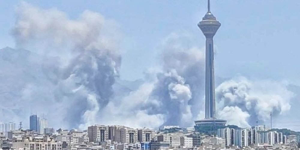 نمای دور از بمباران تهران که در آن برج میلاد دیده می شود و دورتر از آن دود به آسمان بلند شده است