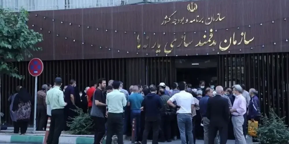 در روبروی سازمان هدفمندی یارانه ها حدود چهل نفر زن و مرد ایستاده اند. به نظر می رسد اعتراض دارند