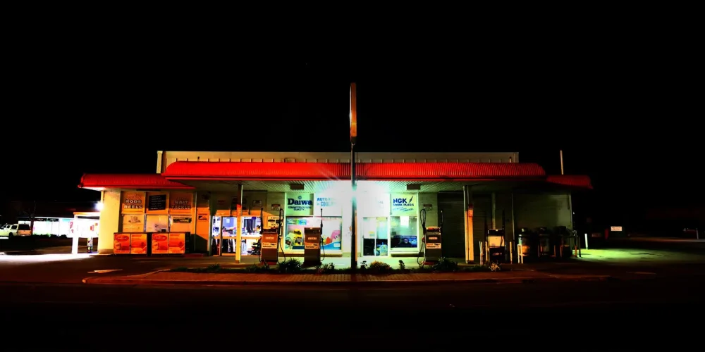 تصویر یک پمپ بنزین در آمریکا. تصویر در شب است و چراغ های بمب بنزین روشن. کسی داخل آن نیست