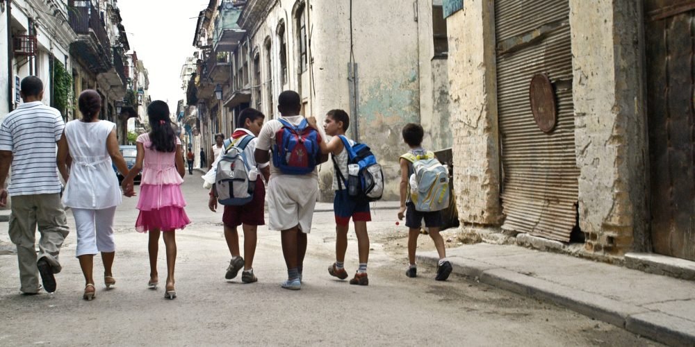 چند کودک در حال بازگشت از مدرسه در خیابان های فرسوده در کوبا